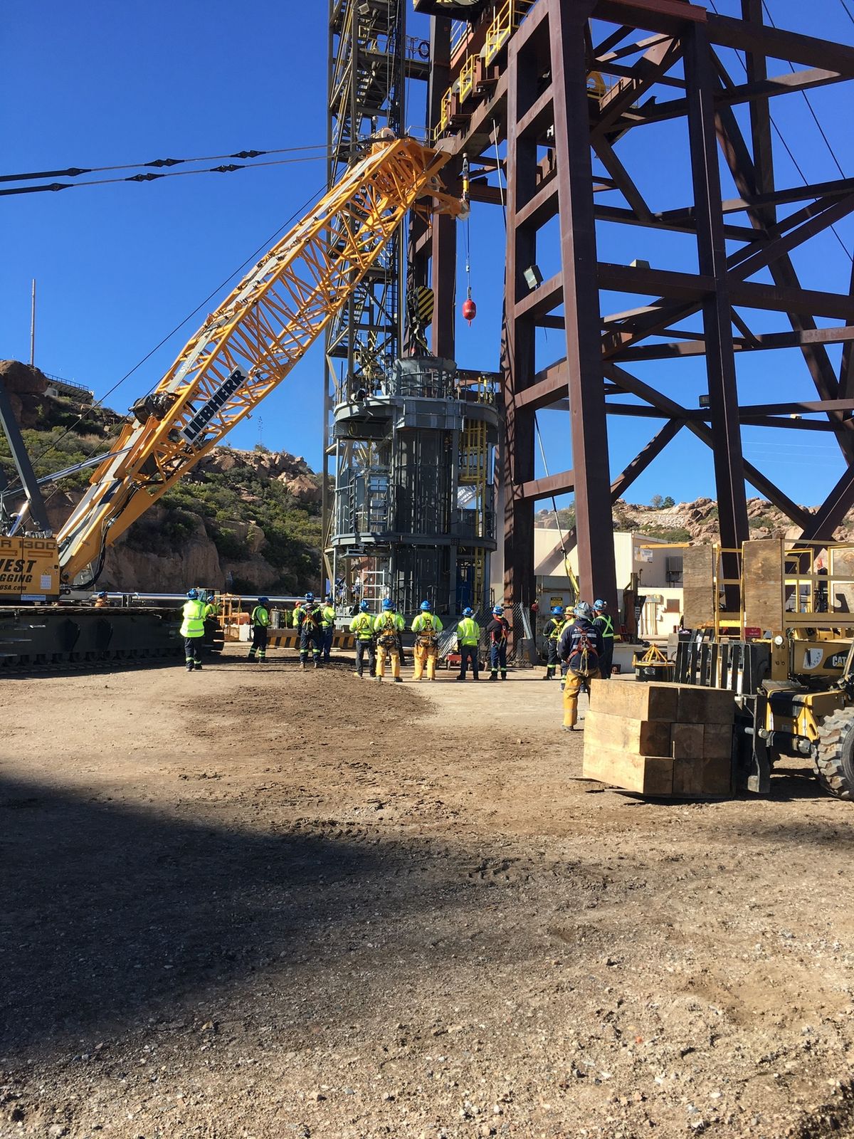Crew in fall protection during a Galloway work platform lift with a Liebherr crawler crane at the headframe