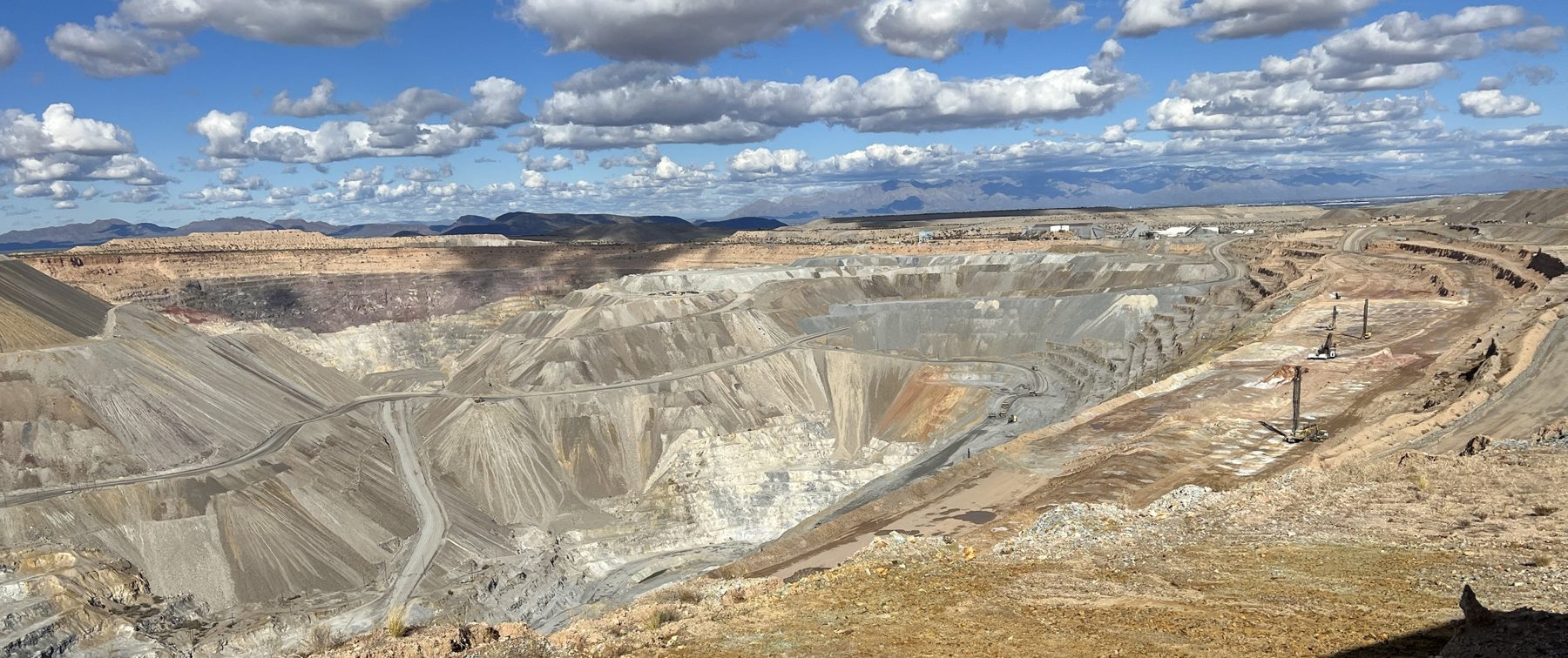 Large open-pit copper mine with drills working the benches