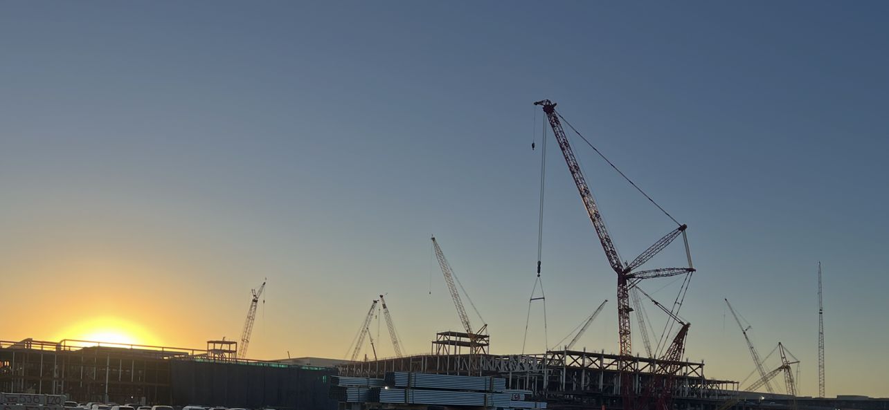 Crawler cranes over a large capital project at sunset